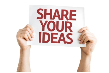 Person holding a sign that says "Share Your Ideas" promoting collaboration and idea sharing in educational settings.