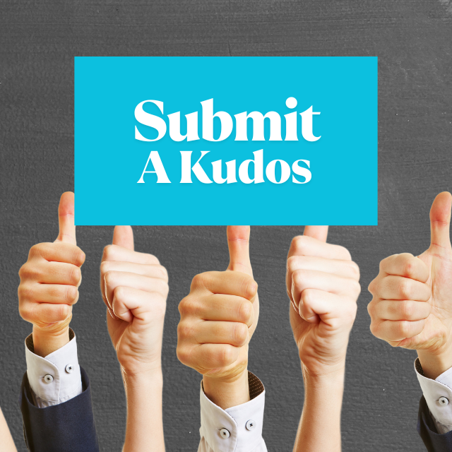 Group of professional individuals holding thumbs up with a "Submit A Kudos" sign, highlighting recognition and appreciation in an academic setting.