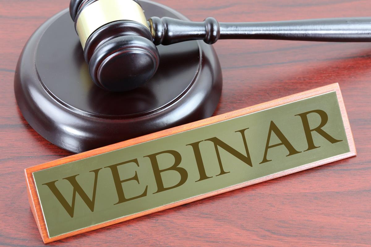 A wooden gavel rests on its block next to a wooden sign reading webinar.